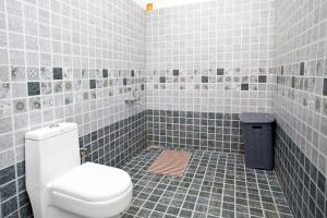 a tiled bathroom with a toilet and a trash can at StayVista at Villa Misty Oaks with Breakfast in Ooty +15 photos