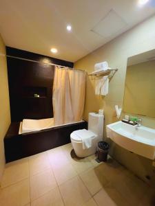 a bathroom with a toilet and a sink and a tub at 88 Courtyard Hotel in Manila