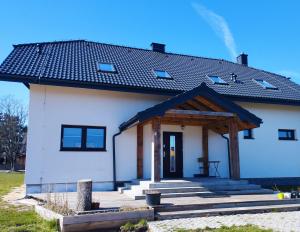 a small white house with a black roof at Dom z widokiem in Smołdzino