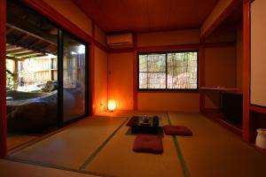 a room with orange walls and a table and windows at YamakawaZENZO in Oguni