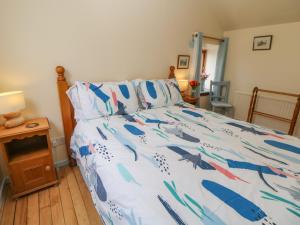 Un dormitorio con una cama con un edredón azul y blanco. en The Old Bakery Barn, en Bakewell