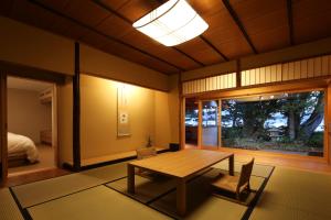 een kamer met een tafel en stoelen en een bed bij Monjusou Shourotei in Miyazu