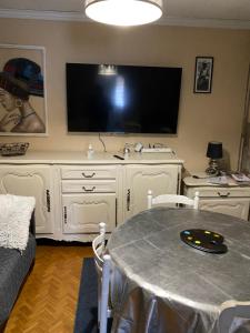 sala de estar con mesa y TV grande en Petite maison atypique animaux acceptés en Les Forges