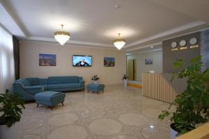 a waiting room with a blue couch and a tv at Xabib&son's hotel in Bukhara