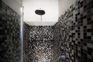 y baño con ducha y azulejos blancos y negros. en Guesthouse Coronari Courtyard, en Roma