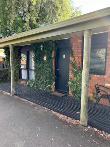 a brick house with a porch with a bench on it at Best Western Colonial Village Motel in Warrnambool