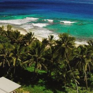 - une vue sur la plage bordée de palmiers et l'océan dans l'établissement Barefoot Base Tupapa, à Rarotonga