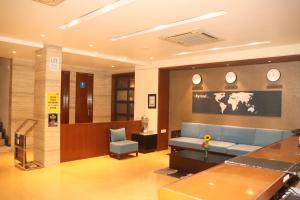 a waiting room with a blue couch and clocks on the wall at Kyriad Hotel Indore by OTHPL in Indore
