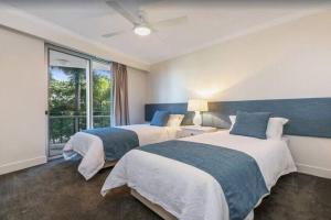 a bedroom with two beds and a window at Palm Springs - Hosted by Burleigh Letting in Gold Coast