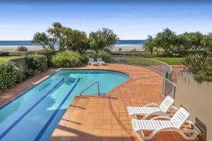 a swimming pool with two chairs and a beach at Palm Springs - Hosted by Burleigh Letting in Gold Coast