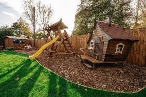 a backyard with a playground with a house and a slide at Bespoke Holiday Home With Private Pool And Hot Tub, Sleeps 8 Ref 34073p in King's Lynn