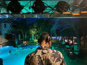 a man wearing headphones looking at a pool at night at Jaguar House Resort Muine in Mui Ne