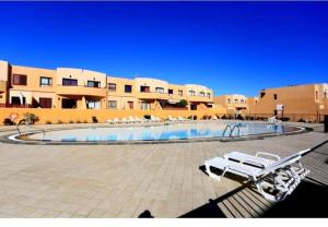 a swimming pool with lounge chairs in front of a building at Fuertevida in Caleta De Fuste