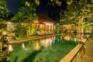 a swimming pool in front of a house at night at Villa Kampung Kecil in Sanur