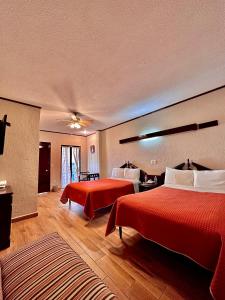 Habitación de hotel con 2 camas con sábanas rojas en Hotel Boutique Tehuacan, en Tehuacán