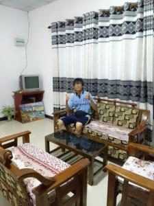 un jeune garçon assis sur un canapé dans une pièce dans l'établissement Kandyan Rest, à Wasgamuwa