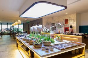 una línea de buffet con plantas en un restaurante en The Glomad Danang Hotel en Da Nang