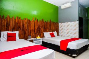 two beds in a room with a green wall at RedDoorz Syariah @ Colomadu 2 in Solo