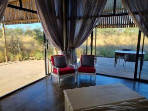 um quarto com uma mesa e duas cadeiras e uma mesa e uma mesa em Hackberry House Bushwillow Cottage (Off Grid) em Khemsbok