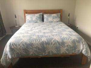 a bed with a white comforter with palm trees on it at #5 on Blenheim St in Renwick