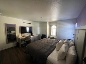 a bedroom with a bed and a desk and a television at The Aqua Pacific Hotel in Santa Cruz