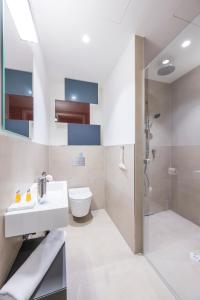 a bathroom with a sink and a toilet and a shower at Luxury Suites Renngasse in Vienna