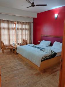 1 dormitorio con 1 cama grande y pared roja en TSASKAN hotel en Leh