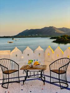 a table and two chairs with a table and water at Hotel Vallabh with lake facing balcony in Udaipur