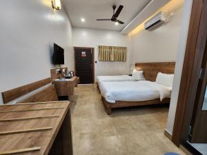 ジョールハートにあるHotel Gulmohar Grandのベッド2台とテレビが備わるホテルルームです。