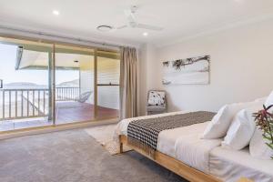 a bedroom with a bed and a balcony at Aria waterview in Point Clare
