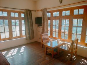 ein Esszimmer mit einem Tisch, Stühlen und Fenstern in der Unterkunft TSASKAN hotel in Leh