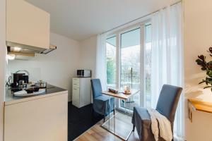 una pequeña cocina con mesa, sillas y ventana en M2 Living Apartment No 5, en Prerow