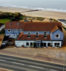 a blue house with a beach in the background at Seals Bacton in Bacton
