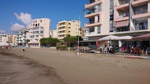 a beach with buildings and people sitting at tables at Sunlit Coast Apartment Durrës in Durrës