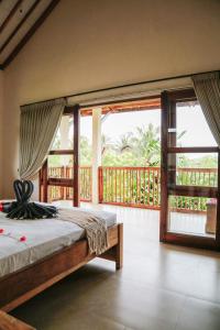 a bedroom with a bed and a balcony with windows at Owa Lodge Areguling in Kuta Lombok