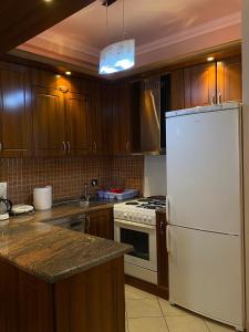 a kitchen with wooden cabinets and a white refrigerator at Cloud8 Apt with Castle View, 7km from the Beach in Lezhë