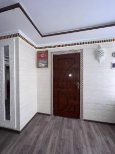 Habitación con puerta de madera y suelo de madera. en Hotel Guest House GOLDEN DEGREZ en Bukhara