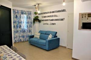 a blue couch in a living room with a wall with words at LA CASA DI CHLOE in Marzamemi