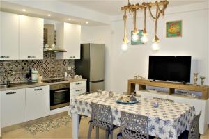 a kitchen with a table with chairs and a television at LA CASA DI CHLOE in Marzamemi