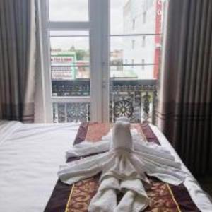 - un lit avec des serviettes blanches devant une fenêtre dans l'établissement Kim Ngân Hotel Buôn Ma Thuột, à Buôn Ma Thuột