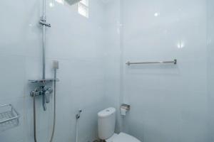 a white bathroom with a shower and a toilet at Urbanview Hotel Gita Inn Bali in Denpasar