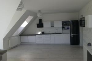 uma cozinha com armários brancos e um frigorífico preto em Kama Apartament Kamień Pomorski em Kamień Pomorski