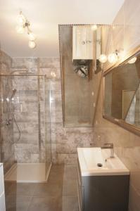 a bathroom with a shower and a sink and a mirror at Kama Apartament Kamień Pomorski in Kamień Pomorski