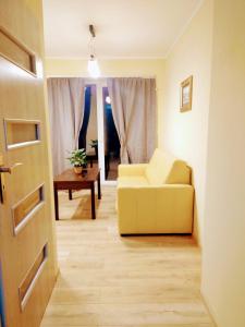 ein Wohnzimmer mit einem gelben Sofa und einem Tisch in der Unterkunft ChillHouse 2 in Mrągowo