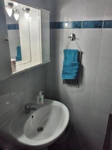 een badkamer met een wastafel, een spiegel en blauwe handdoeken bij VagelisHome in Komotini