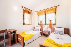 une chambre avec deux lits, un bureau et une fenêtre dans l'établissement Casa D' Irene Rhodes, à Lakhania