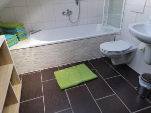 ein Badezimmer mit einem WC, einer Badewanne und einem grünen Teppich in der Unterkunft Eifelferienkurth in Buir