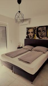 uma cama grande num quarto com cartazes na parede em SPA RESIDENZ NEUSIEDL APPARTMENTS em Neusiedl am See