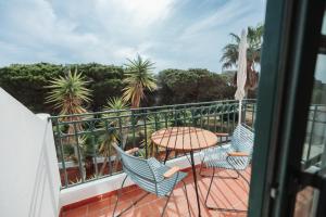 a balcony with a table and chairs and palm trees at Casa Velha Apartments - Adults friendly in Albufeira