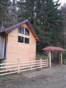 una pequeña casa de madera con una valla y una puerta en Rudnička čarolija, en Rudnik
